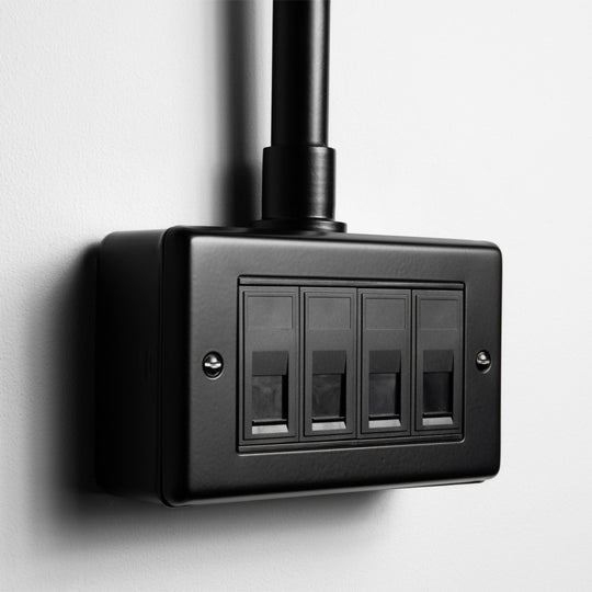Matt Black 4 Gang RJ45 Socket With Back Box And Conduit On A Light Grey Background
