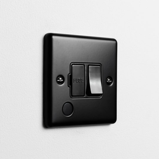 Matt Black Switched Fused Connection Switch With Flex Outlet With Black Insert On Light Grey Background