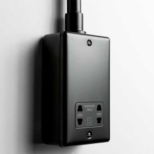 Matt Black Dual Voltage Shaver Socket With Back Box And Conduit On A Light Grey Background