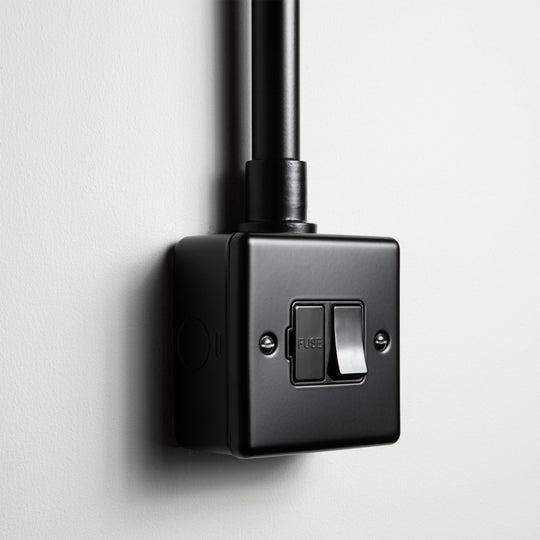 Matt Black Switched Fused Connection Switch With Back Box And Conduit On A Light Grey Background