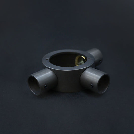 A dark bronze 20mm conduit tee box with three outlets, placed against a dark background.