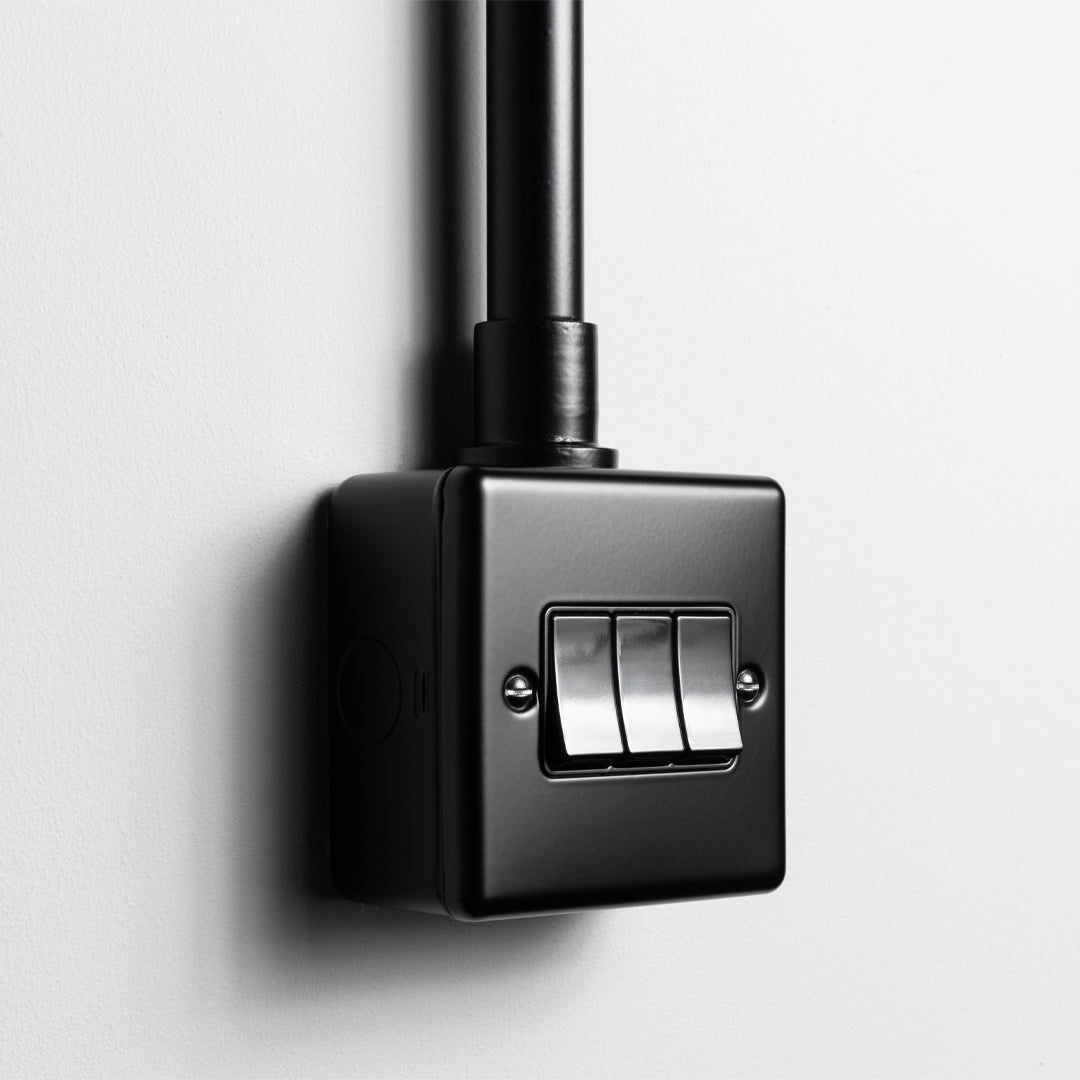 Matt Black 3 Gang 2 Way Switch  With Back Box And Conduit On A Light Grey Background